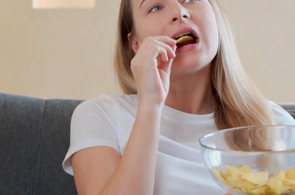 Une femme assise mange des chips